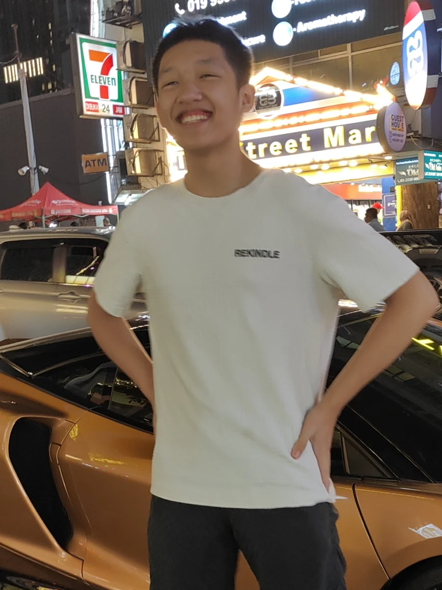 Quang trên một con phố Kuala Lumpur buổi tối, đang cười trước những biển hiệu
