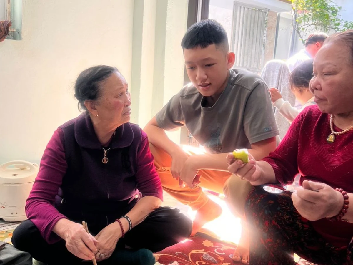 Quang ngồi cùng hai người bà, chia nhau một miếng trái cây